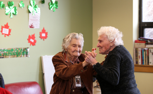 Two elderly women dancing in a public housing building